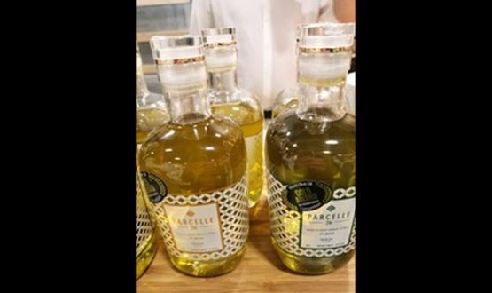 Bouteilles d'huile d'olive premium de la marque Parcelle, exposées sur un comptoir en bois.