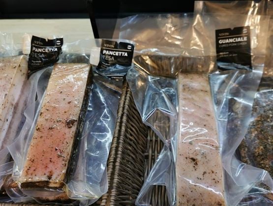 Paniers garnis de charcuteries artisanales sous vide, avec notamment des morceaux de pancetta tesa et de guanciale de la marque VIVIN. Les pièces de viande sont présentées de manière soignée, mettant en valeur leur texture marbrée et leur assaisonnement.