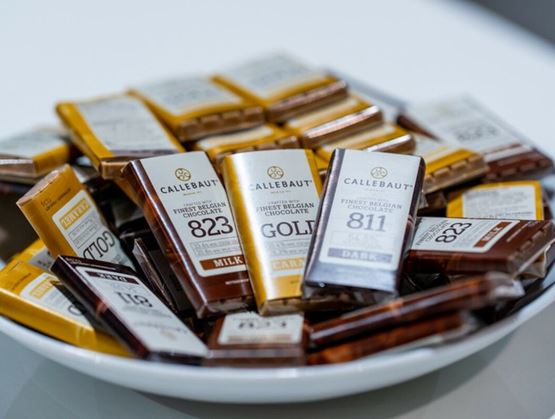 Assiette remplie de mini-tablettes de chocolat Callebaut aux emballages variés : lait, noir, caramel… Chaque étiquette indique le pourcentage de cacao et le type de chocolat belge haut de gamme. Présentation soignée et gourmande.