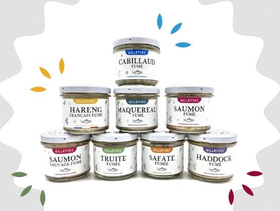 Gamme de rillettes de poissons fumés artisanales en bocaux, incluant cabillaud, hareng, maquereau, saumon, truite, haddock et safate, joliment présentés en pyramide sur fond décoratif.