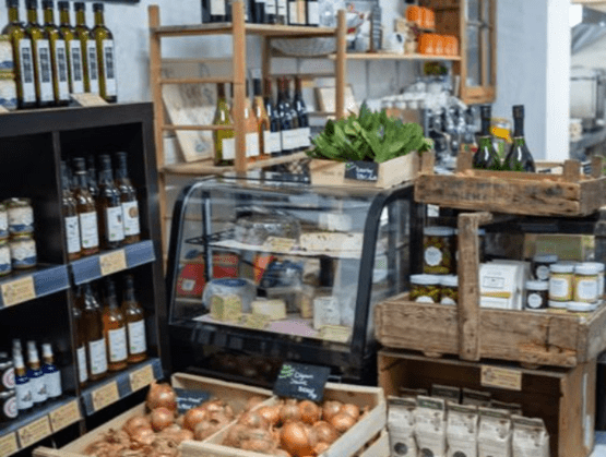 Vue de l’intérieur de Maison Paulette, épicerie-cafétéria située au Mesnil-Saint-Denis, présentant un étalage soigné de produits frais et locaux : fromages en vitrine réfrigérée, bouteilles de vin, condiments, légumes de saison et conserves artisanales, le tout dans une ambiance rustique et authentique.