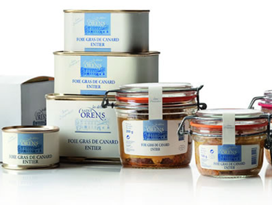 : Gamme de foie gras entier de canard des Délices de Saint Orens, présentée en bocaux en verre et boîtes métalliques aux étiquettes bleu et blanc.
