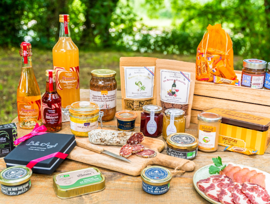 Assortiment de produits gastronomiques du terroir français exposés en plein air : charcuteries, tartinables, confitures, boissons artisanales, condiments, et douceurs régionales présentés sur une table en bois, illustrant la richesse culinaire des régions de France.