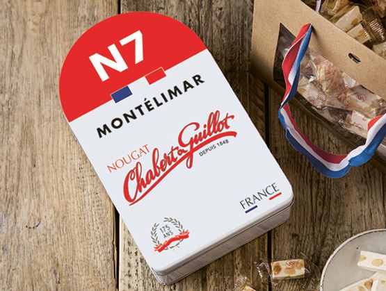 Boite de nougats de la marque Chabert et Guillot posée sur une table en bois à coté d'un sachet de nougats