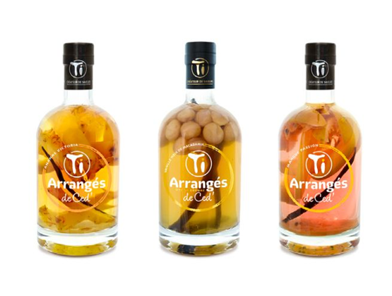 trois bouteilles du rhum arrangé TI CED alignées sur fond blanc