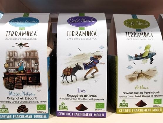 Trois paquets de café Terramoka sont alignés sur une étagère, avec des illustrations distinctes et les noms Mister Nelson, Inès et Arthur sur les emballages.