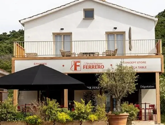 Façade de la boutique Maison Ferrero, combinant épicerie, concept store et table de dégustation, avec terrasse ombragée et végétation.