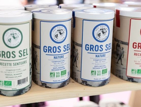 Boîtes de gros sel bio présentées sur une étagère lors d’un salon professionnel.