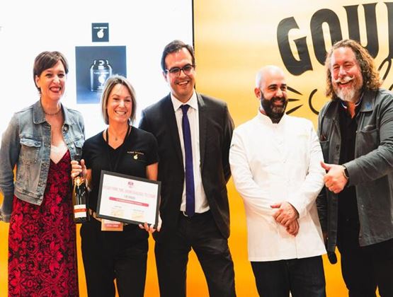 Lauréats et membres du jury posant avec un diplôme et une bouteille sur l’espace Gourmet Selection.