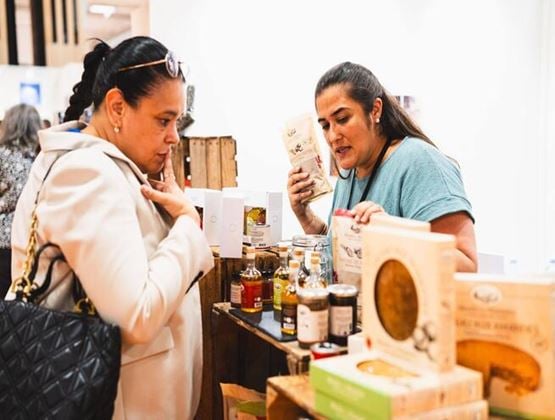 Deux femmes échangeant autour de produits d’épicerie fine présentés sur un stand.