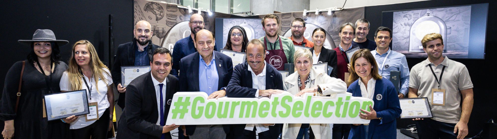 Group photo of award winners and organizers holding a "#GourmetSelection" sign during a prize ceremony at a trade show.