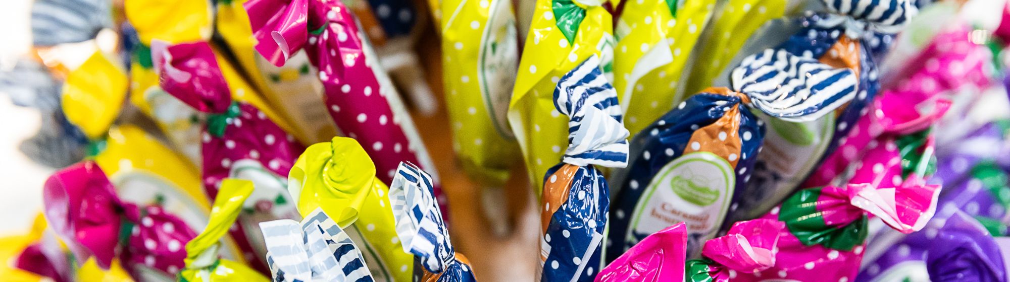 Bonbons emballés dans des papiers colorés à pois, exposés en bouquet sur un stand.