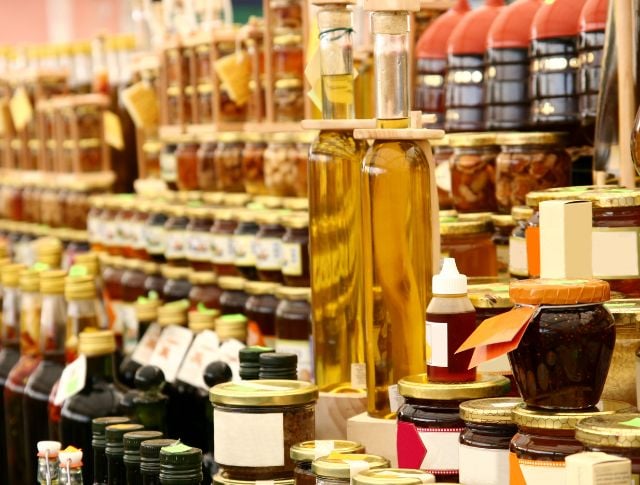 Shelves of a fine food market with bottles of oil, jars of jams, and artisanal preserves