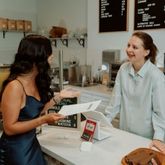Professionnel de l’épicerie échangeant avec un client au comptoir d’une boutique spécialisée, autour de produits gourmets et de conseils personnalisés.