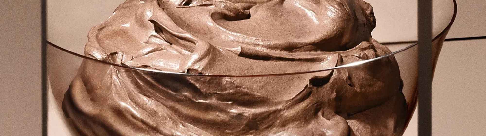 Close-up of a creamy, rich chocolate mousse in a glass, with smooth swirls and a glossy texture.