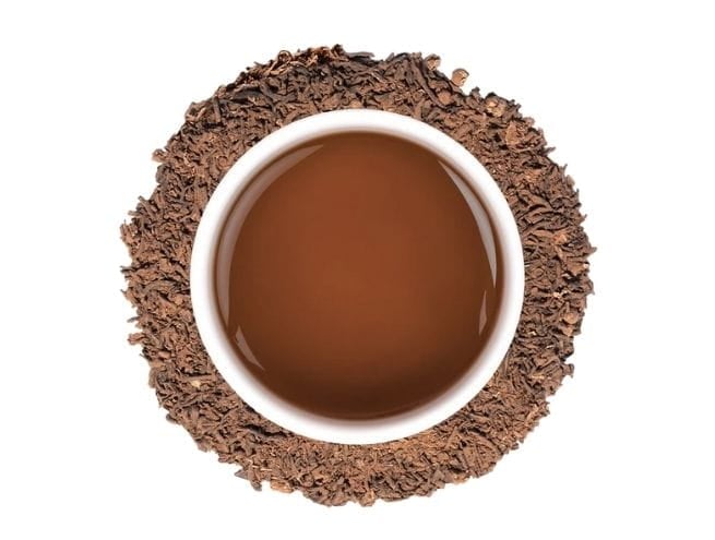 Top view of a cup of mocha surrounded by crushed leaves.