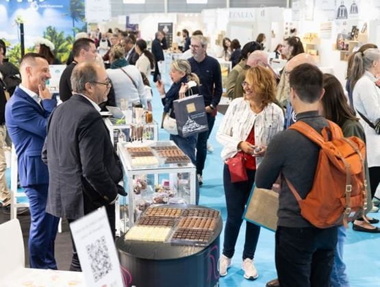 View of a chocolate stand at the Gourmet Selection trade show, with visitors and exhibitors discussing products.