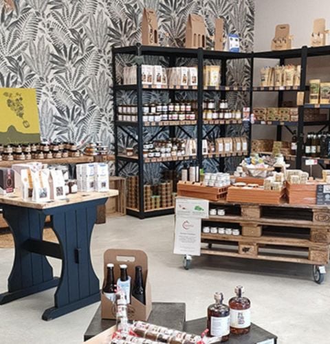 Intérieur convivial et rustique de l’Épicerie Bien & Bon avec des présentoirs en bois proposant une gamme variée de produits locaux.