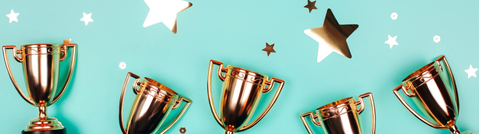 Cinq trophées dorés alignés sur un fond turquoise pour le concours de la meilleure épicerie de france