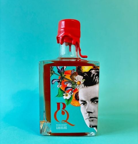 Bouteille de liqueur avec cire rouge fondante et étiquette illustrée, posée sur fond turquoise.