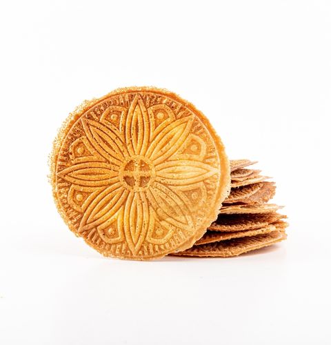 Golden round biscuit with floral patterns, placed in front of a stack of thin biscuits on white background.