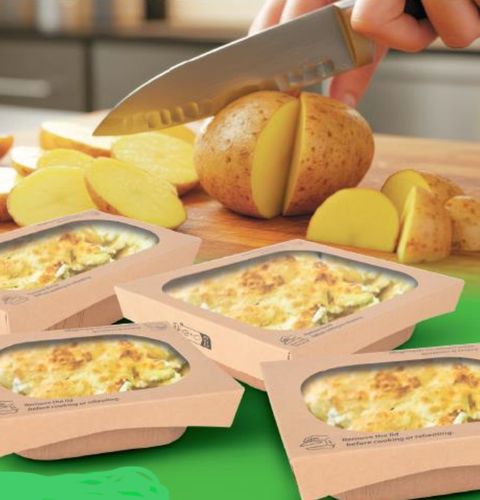Gratin dishes in trays with potatoes being sliced by knife on a wooden board.