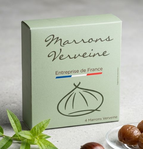 Green box of verbena chestnuts, shown with fresh leaves and glazed chestnuts on the side.