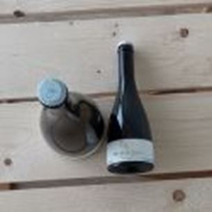 Two wine bottles placed on a light wooden table, photographed from above.