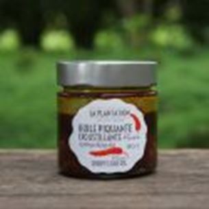 Pot de gelée de pamplemousse sanguine présenté en extérieur avec fond végétal flou.