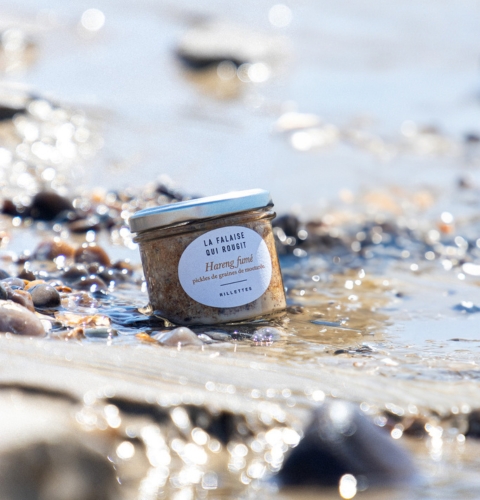 Jar of smoked herring rillettes with pickled mustard seeds, photographed on a light background.