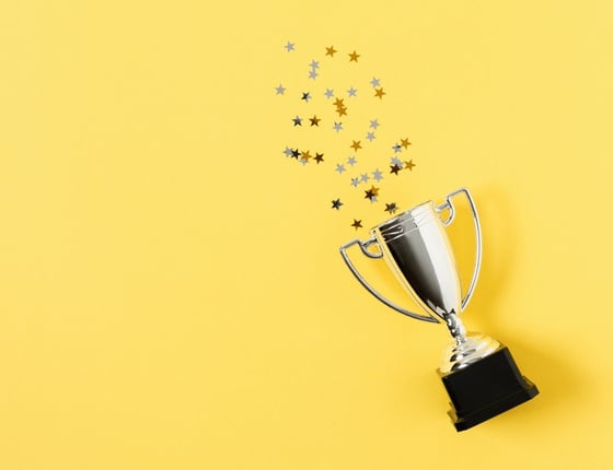 Trophée argenté avec confettis en forme d’étoiles sur fond jaune vif minimaliste.
